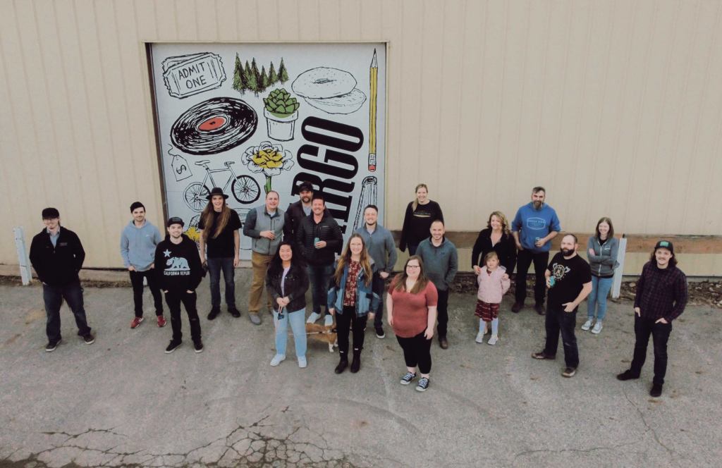 This drone image is shot from above. Below, you can see 19 individuals from Office Sign Company smiling for the camera.