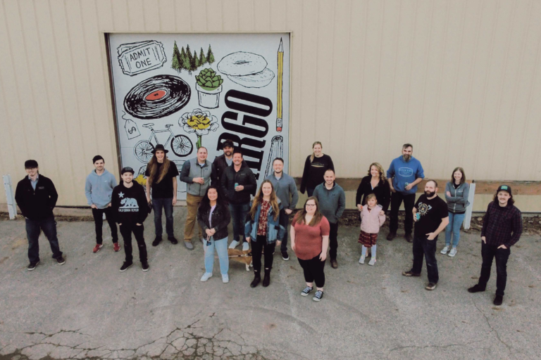 Office Sign Company staff smiles for a picture outside our Production facility as a drone takes the photo from above.